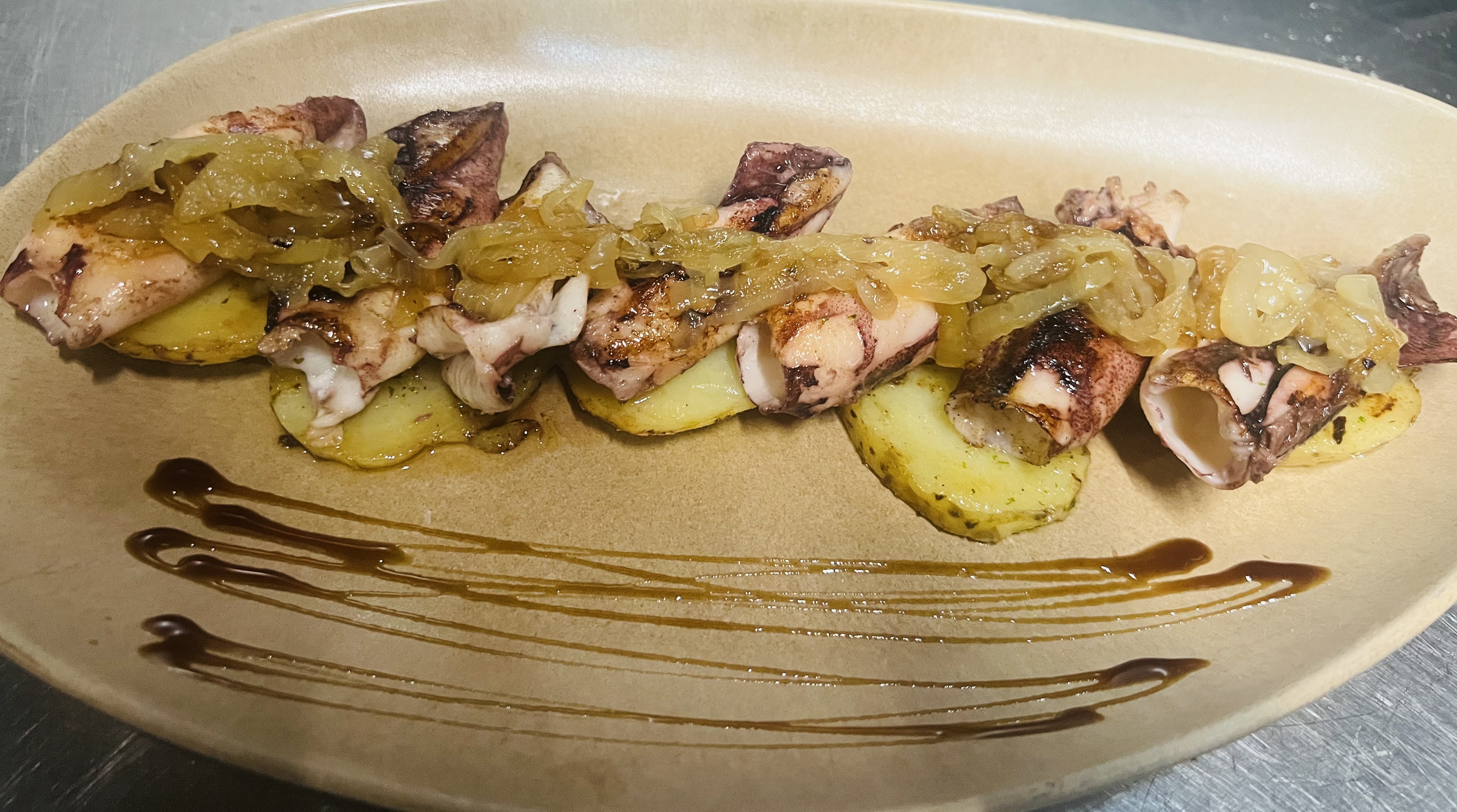Chipirones braseados con patata asada y cebolla confitada