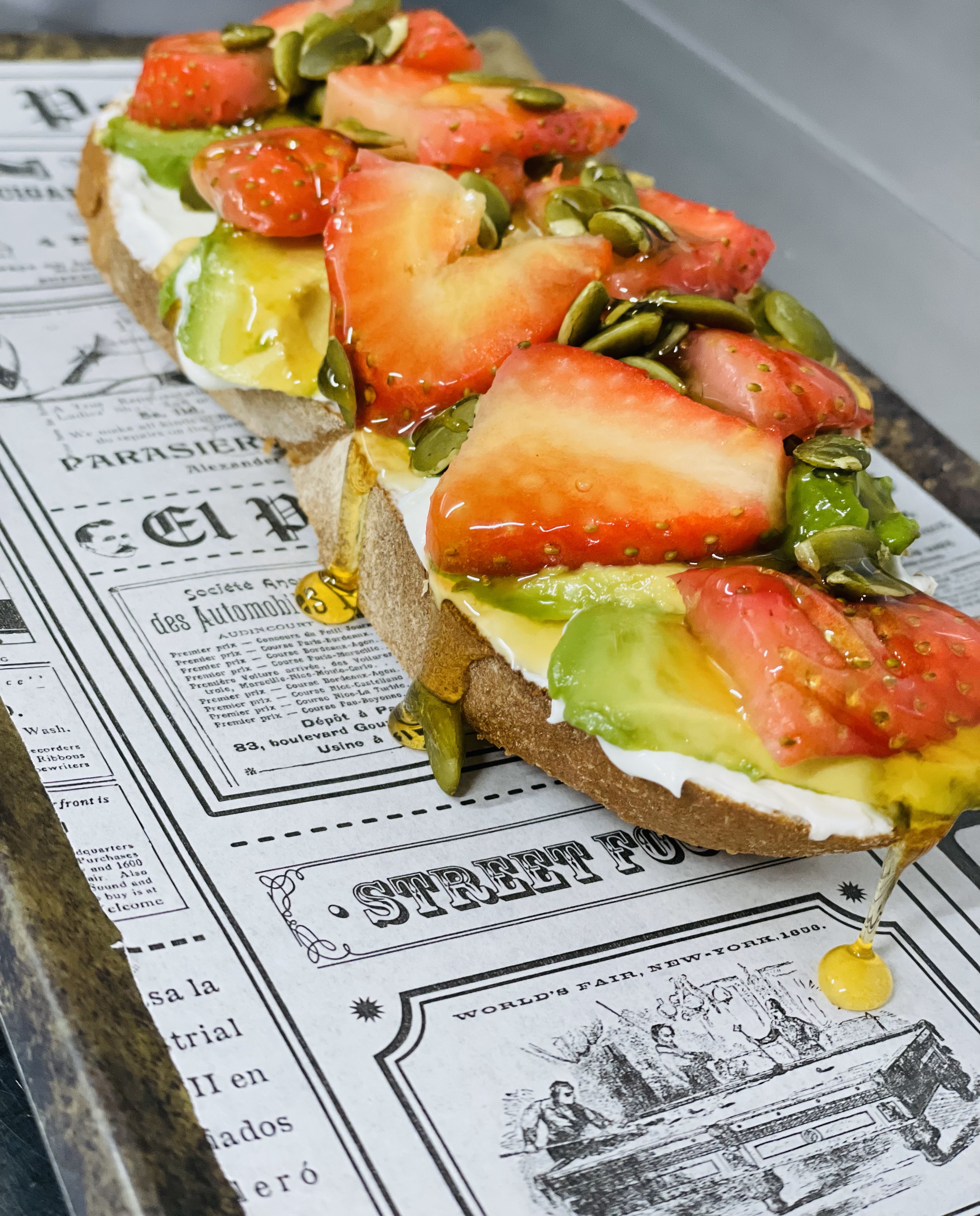 Tostada de crema de yogur con aguacate, fresas, semillas de calabaza y miel + zumo de naranja natural + café