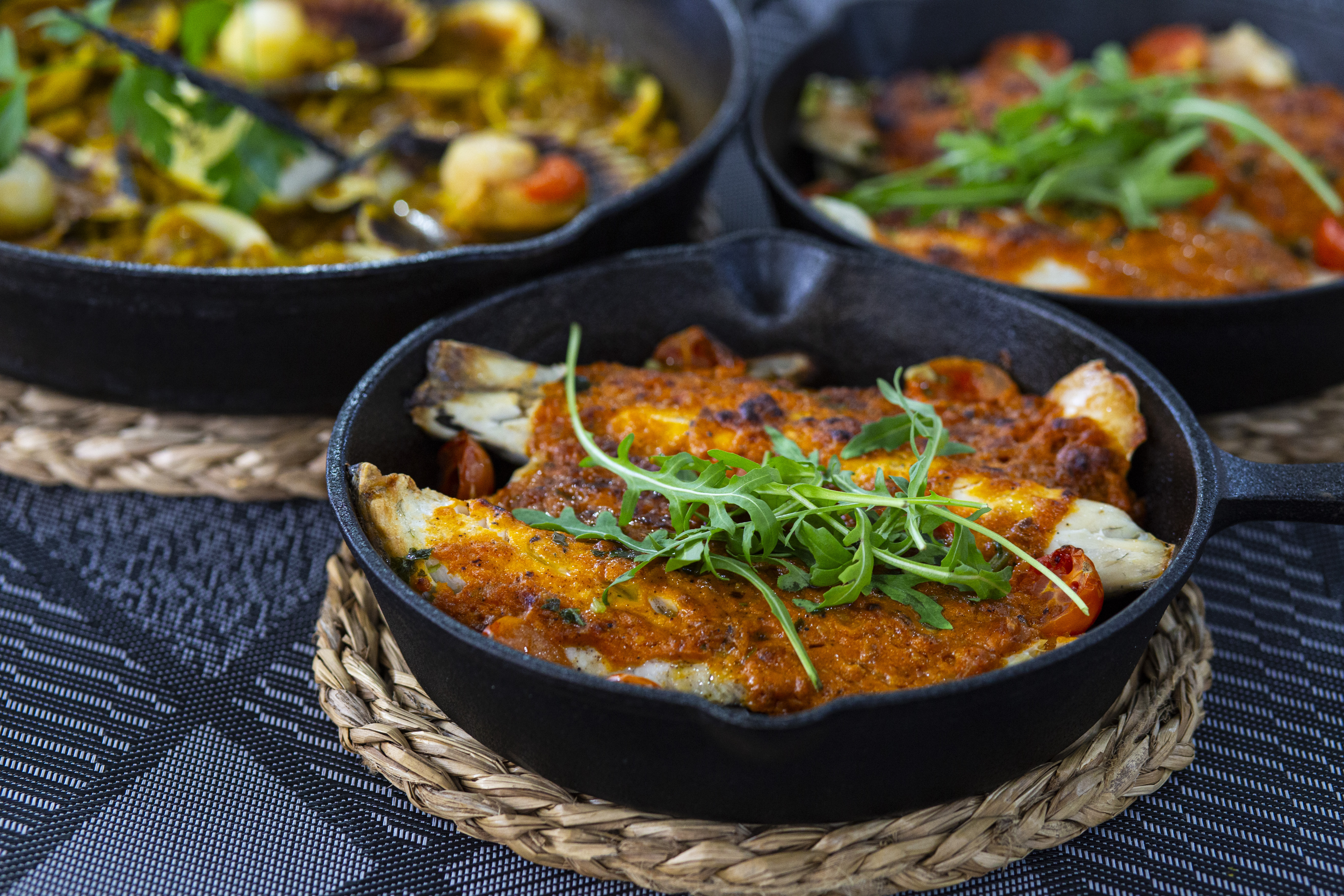 Lubina con salsa romesco al horno, patatas, tomate Cherry, rúcula, ajo y perejil (200g) - 21.99€
